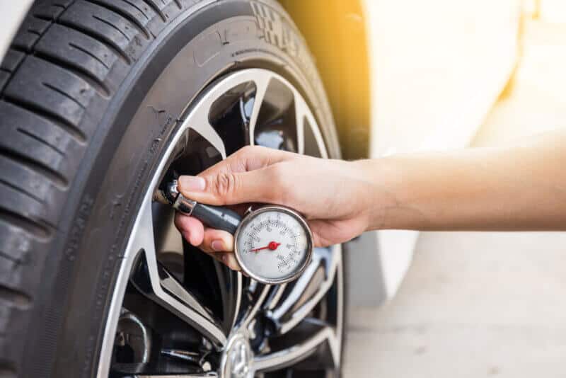 hand with tire pressure gauge checking wheel