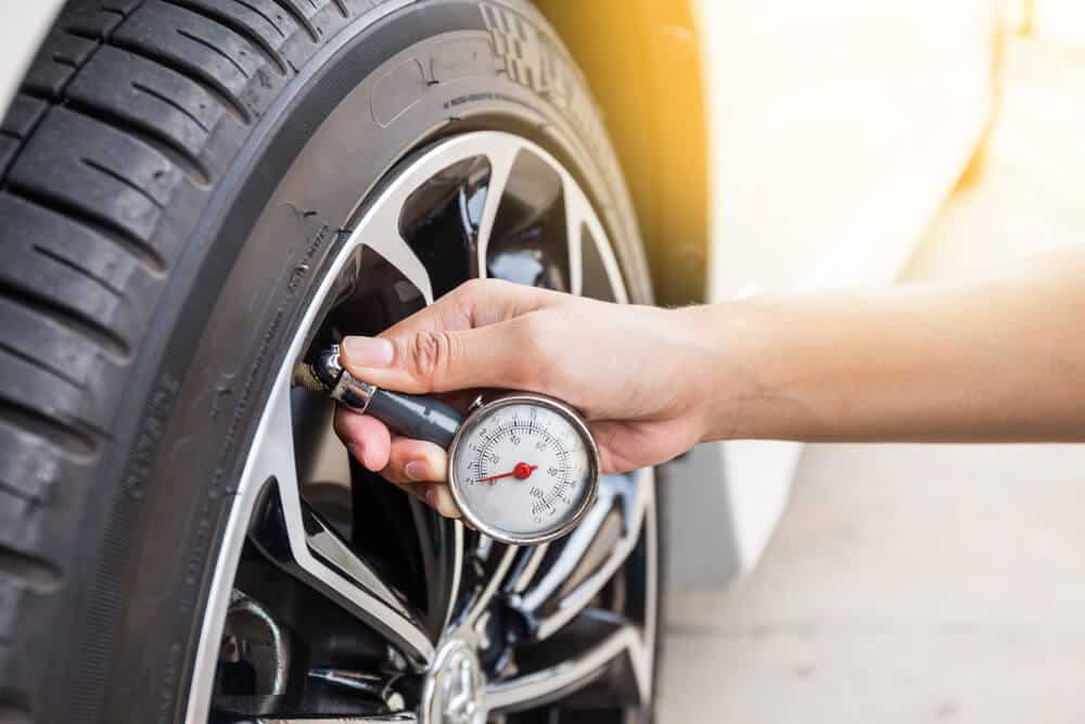 hand with tire pressure gauge checking wheel