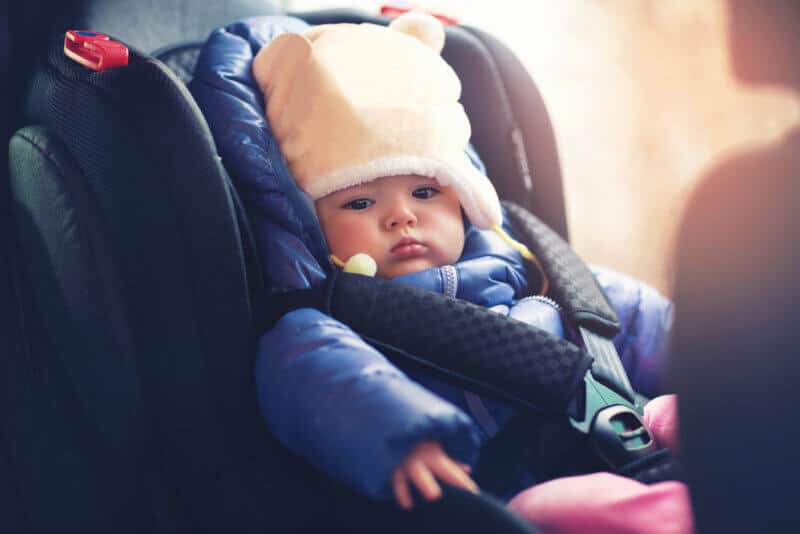 small baby riding inside a car in seat