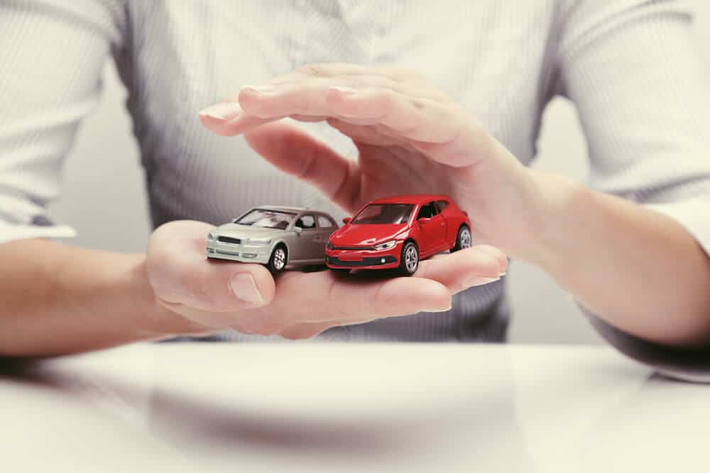 hands holding two toy cars to symbolize multiple car insurance