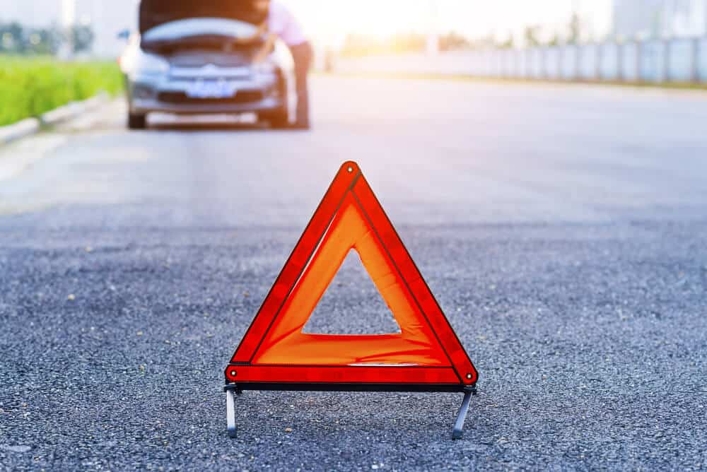 car emergency sign in the middle of a road with a car in the background