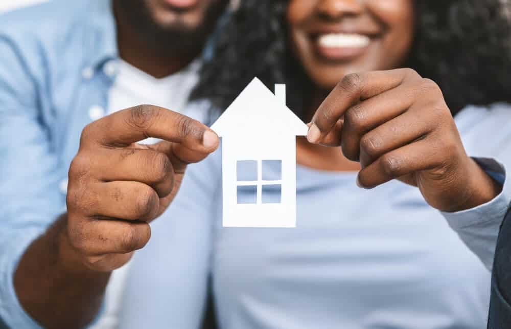 african american couple holding a paper house to simbolize they are renting for the first time