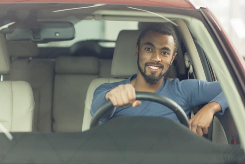 happy african american man in red car drivers seat