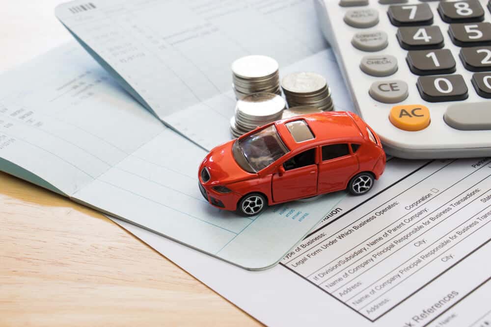 toy car on top of papers and coins to symbolize car insurance