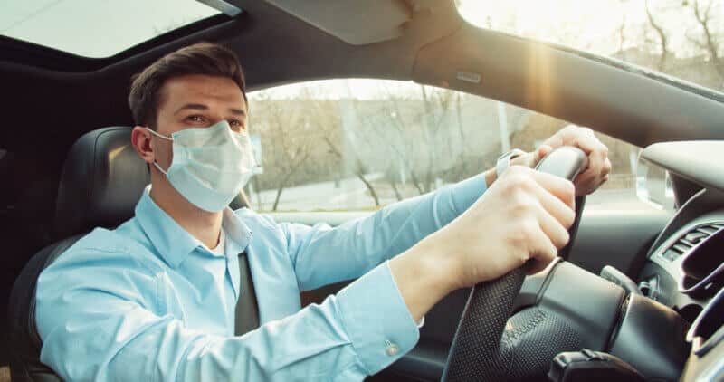 young man driving a car with mask during covid 19