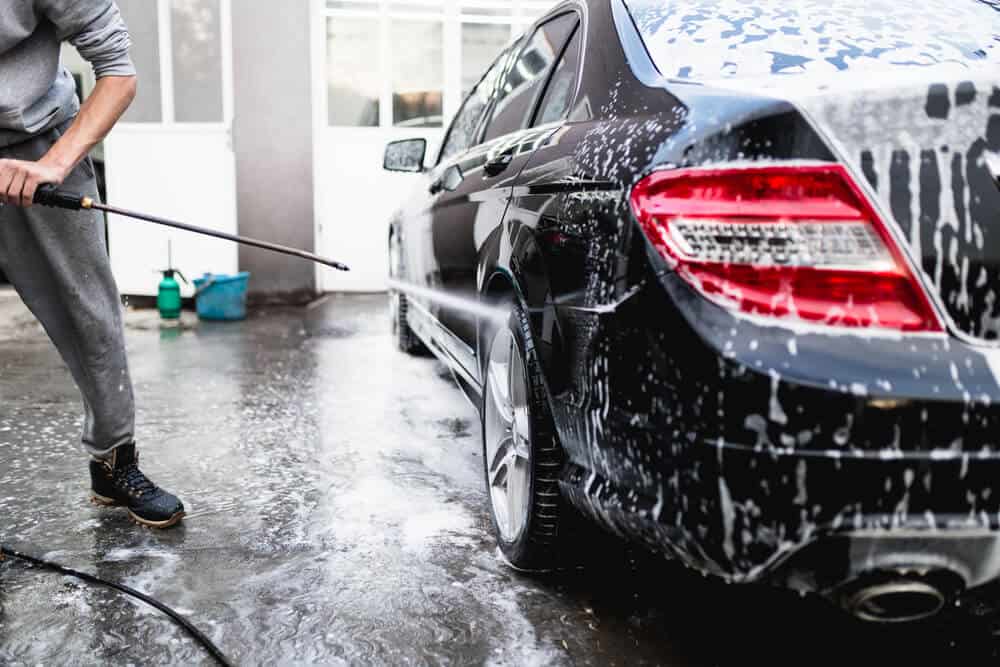 man Cleaning Car Using High Pressure Water