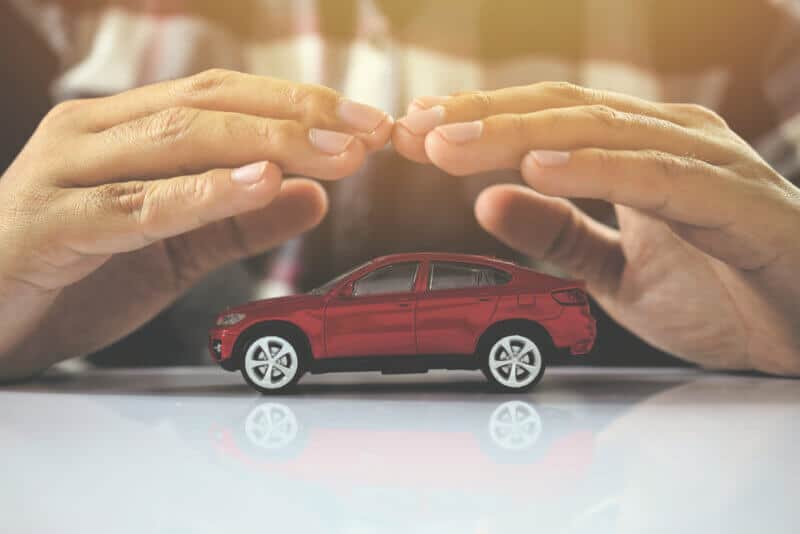 hands over toy car to represent car insurance