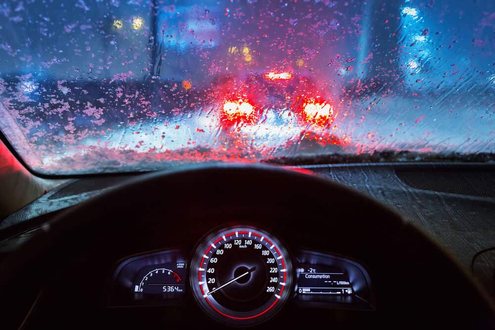 view from a cars drivers seat with rain and traffic in the windshield