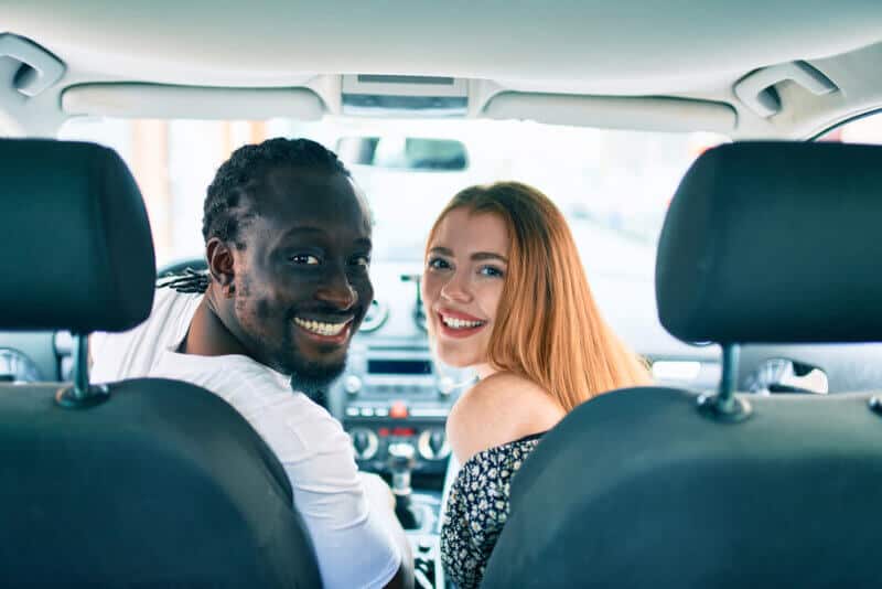 young interracial couple in car looking at the camera smiling