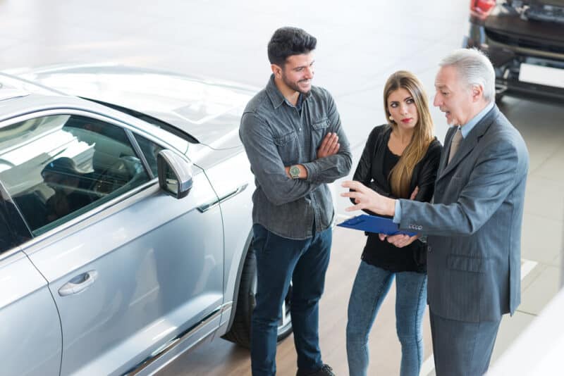 car salesman helping couple find a used car