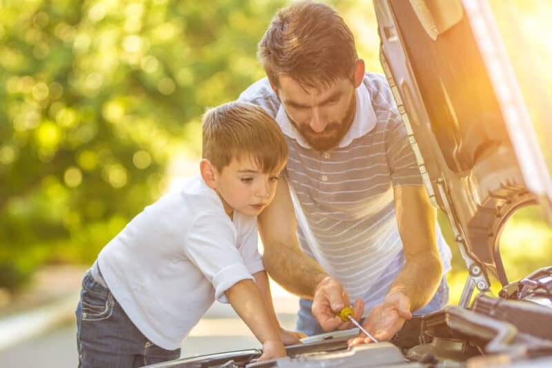 Man and child check the fluids of a car