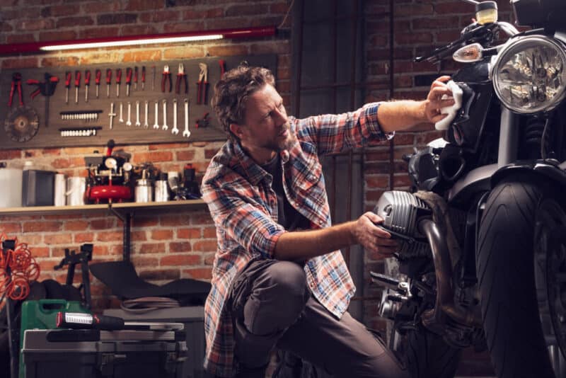 man works on his motorcycle in his garage