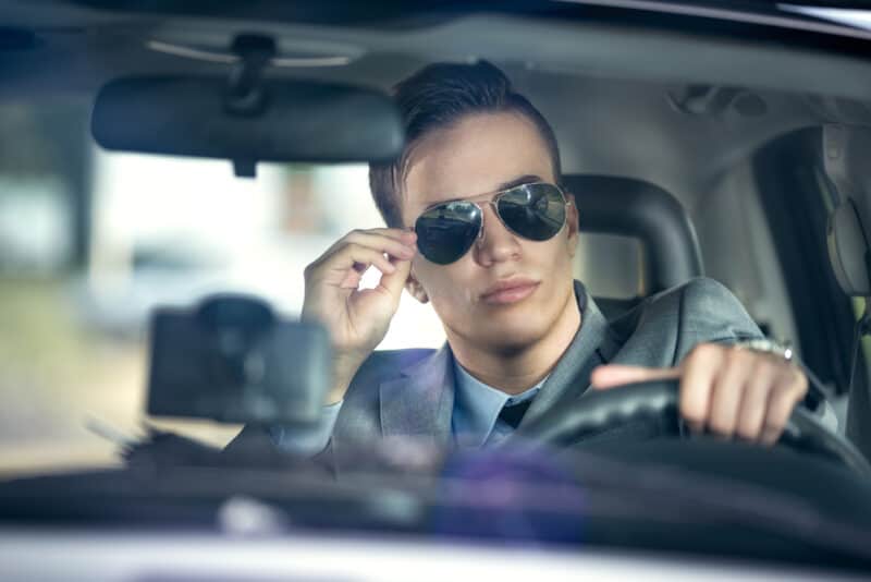 Handsome man in sunglasses behind the wheel of a car