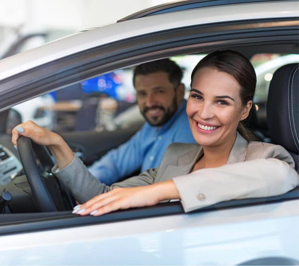 Smiling couple sitting in car looking out driver's side window